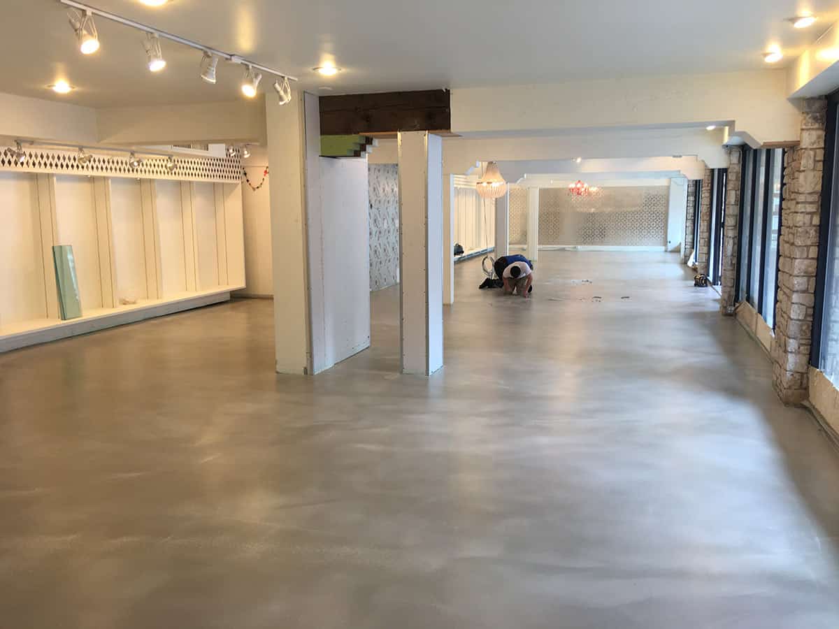 a worker is working to install concrete epoxy caoting of a retail floor